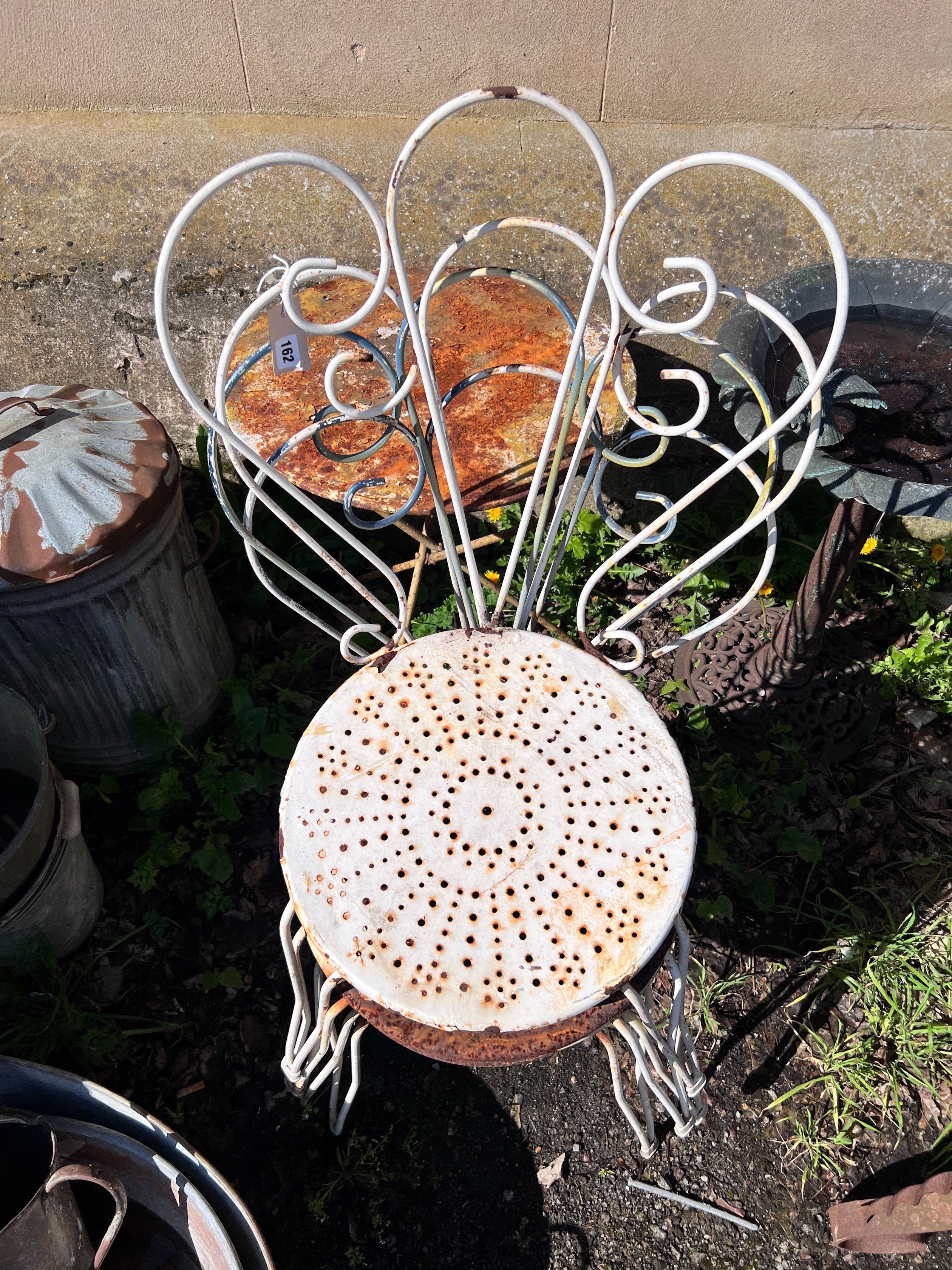 A circular wrought iron garden table and four chairs, diameter 50cm, height 80cm *Please note the sale commences at 9am.